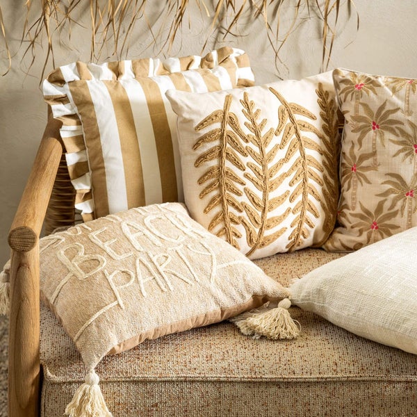 Dekorative Kissen mit verschiedenen Mustern und Texturen auf einem Möbelstück arrangiert.