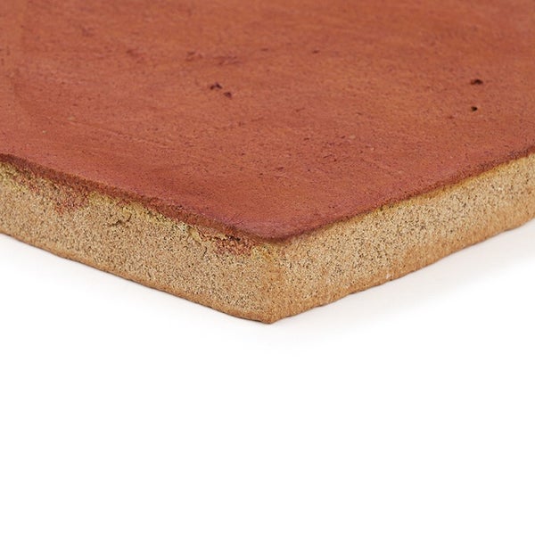 Ein einzelner Terrakotta Bodenbelag mit unebener Oberflächenstruktur und poröser Seitenkante.