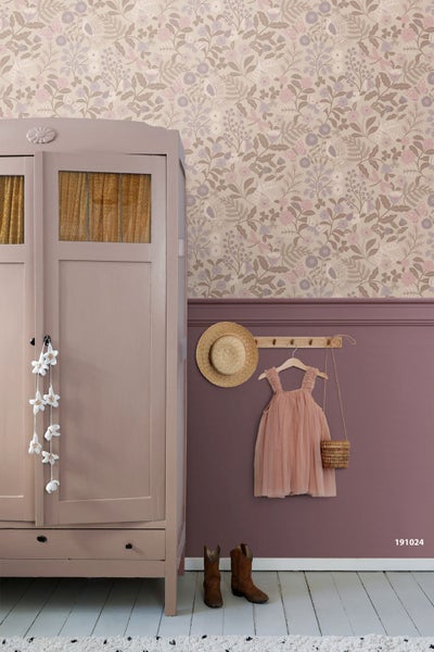 Kinderzimmer mit floral gemusterter Tapete oben, einfarbiger Wandfläche unten, einem Holzschrank und einer Hakenleiste mit Kleidung.