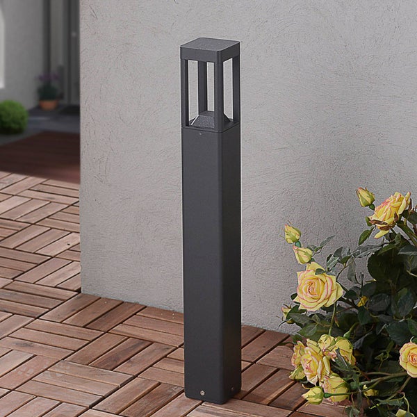 Moderne Außenstandleuchte in Anthrazit auf Holzterrasse neben einer Hauswand und Rosen.