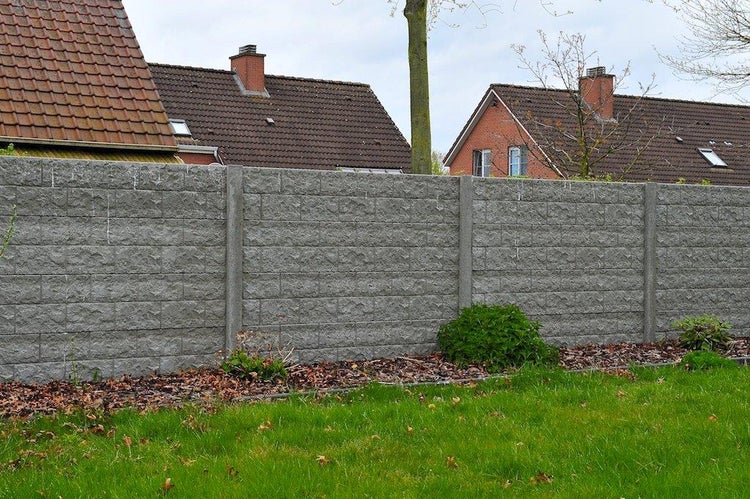 Graue Lärmschutzwand aus Beton mit steinähnlicher Struktur im Garten