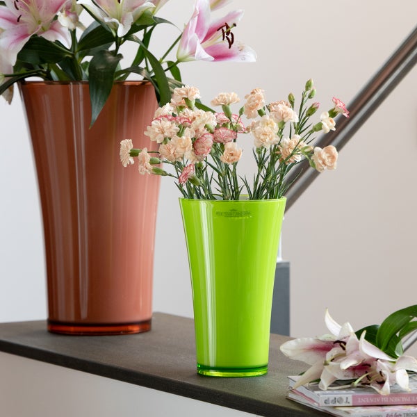 Konische Vasen aus Kunststoff auf einer Ablage, dekoriert mit Schnittblumen wie Lilien und Nelken.