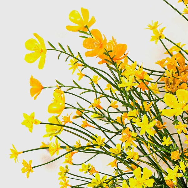 Künstliche gelbe Wiesenblumen mit grünen Stielen.