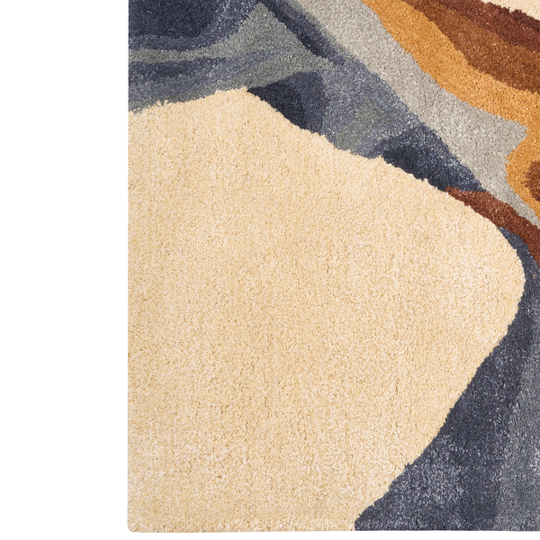 Detail eines handgetufteten Teppichs mit abstraktem Wellenmuster in Beige und Grau sowie dichtem Flor.