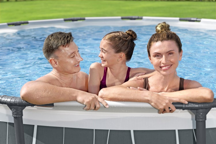 Eine Familie mit Kind entspannt in einem runden Frame Pool im sonnigen Garten.