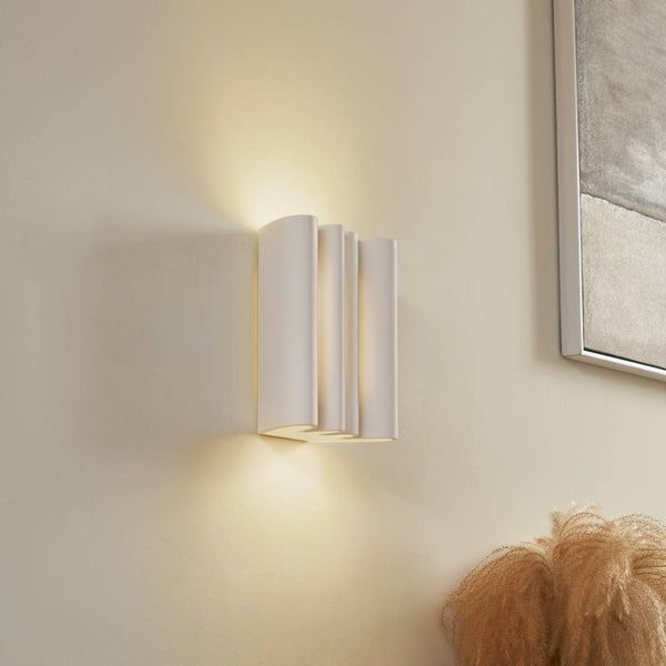 Moderne weiße Wandleuchte mit wellenförmiger Struktur und Lichtaustritt nach oben und unten an einer Wand.