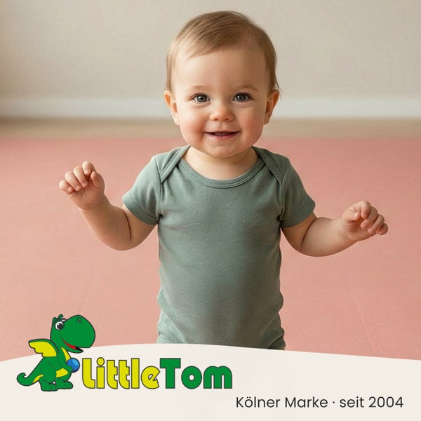 Lächelndes Baby auf einer Schaumstoff-Spielmatte mit LittleTom Logo.