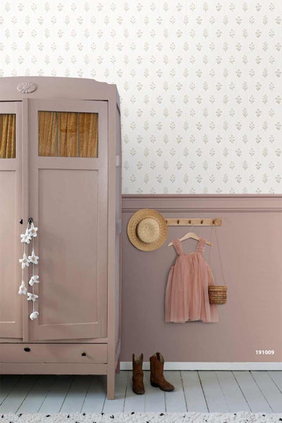 Vintage-Kinderzimmer mit gemusterter Tapete oben und altrosa Wandpaneel unten neben einem Kleiderschrank aus Holz.