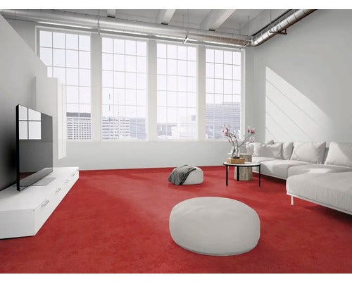 Modernes Wohnzimmer mit rotem Teppichboden, weißem Sofa, Sitzsäcken und großen Fenstern. Industrieller Stil mit sichtbaren Rohrleitungen.