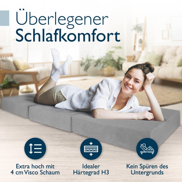Graue Gästematratze mit Dame im Wohnzimmer, extra hoch mit vier Zentimeter Viscoschaum, idealer Härtegrad H3, kein Spüren des Untergrunds.