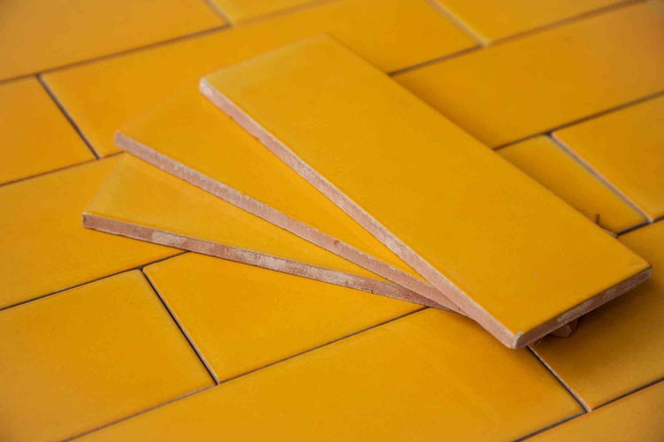 Gelbe rechteckige Wandfliesen aus glänzender Keramik.