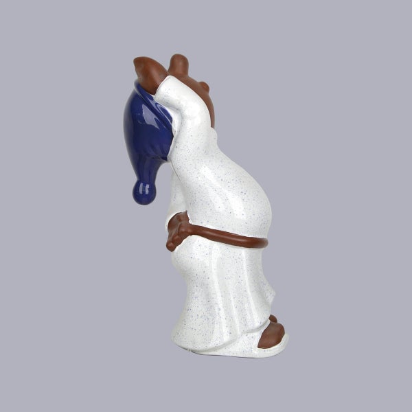 Dekorative Gartenfigur eines Zwergs im weißen gepunkteten Gewand mit blauer Mütze. Seitenansicht.