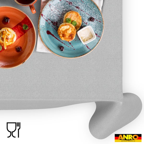 Graue Textiltischdecke von ANRO mit feiner Struktur, lebensmittelecht, auf einem gedeckten Tisch mit Speisen. ANRO Deutsche Manufaktur Logo.
