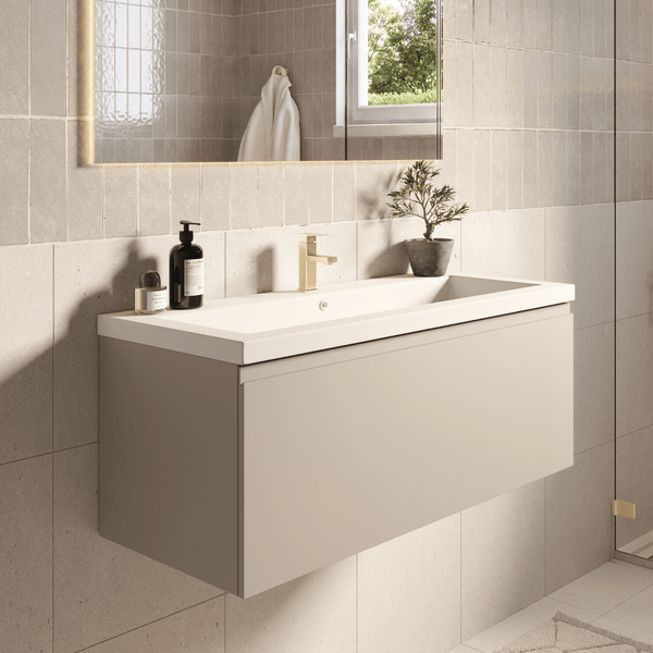Modernes Badezimmer mit beigem wandhängendem Waschtischunterschrank, weißem Waschbecken, goldener Armatur und Spiegel vor gefliester Wand.