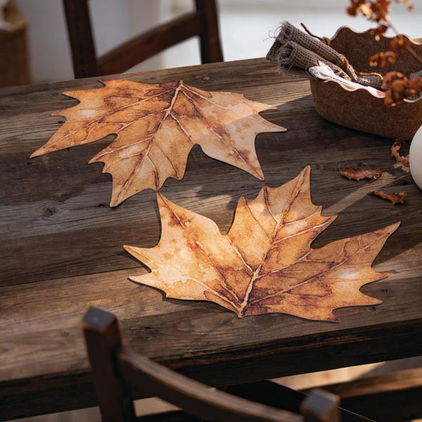 Zwei Tischsets in herbstlicher Ahornblattform auf einem rustikalen Holztisch als Tischdekoration.