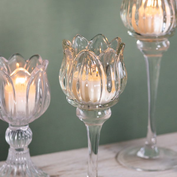 Kerzenhalter aus Glas in Tulpenform mit brennenden Teelichtern auf Stielen in verschiedenen Höhen.