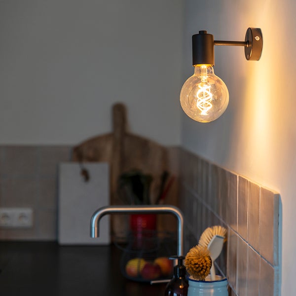 Wandleuchte aus schwarzem Metall mit einer Globe-LED-Lampe und Spiralfilament in einer modern eingerichteten Küche.