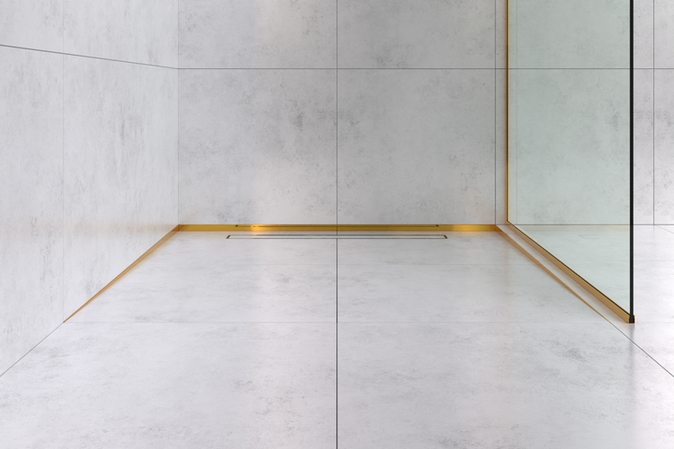 Begehbare Dusche mit hellgrauen Fliesen in Betonoptik, goldfarbenen Abschlussprofilen und integrierter Duschrinne.