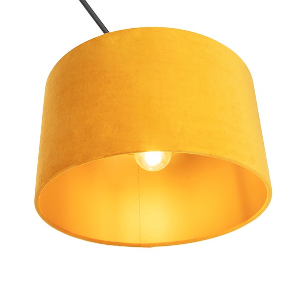 Runde Pendelleuchte mit gelbem Samtschirm und leuchtendem Leuchtmittel.