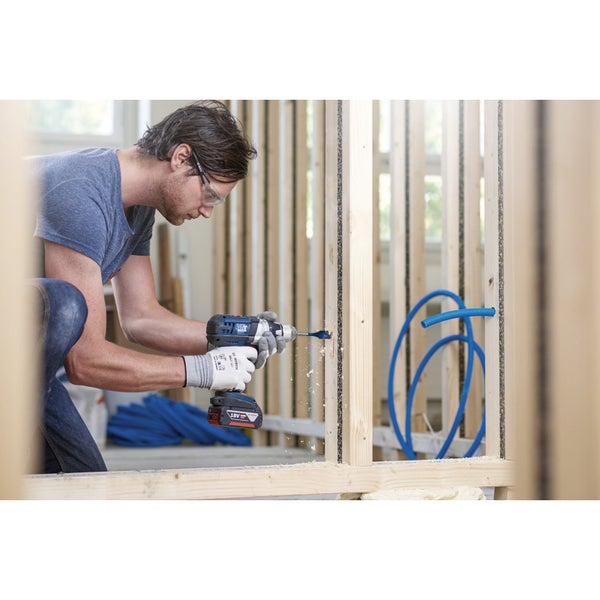 Ein Mann bohrt mit einem Akku-Bohrschrauber ein Loch in eine Holzwand. Sicherheitsbrille und Arbeitshandschuhe werden getragen.