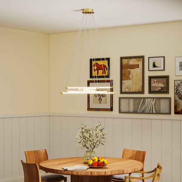 Moderne Pendelleuchte mit fünf verstellbaren LED-Lichtröhren und goldfarbenen Details über einem Holztisch in einem hellen Esszimmer.