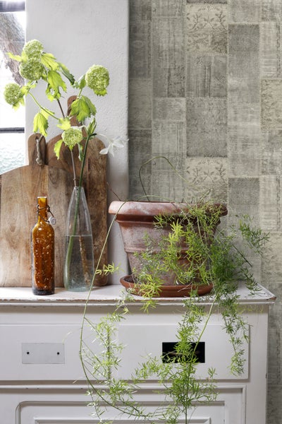 Wandgestaltung mit Patchwork Tapete, Dekoration mit Pflanzen und Vasen auf einem Sideboard.