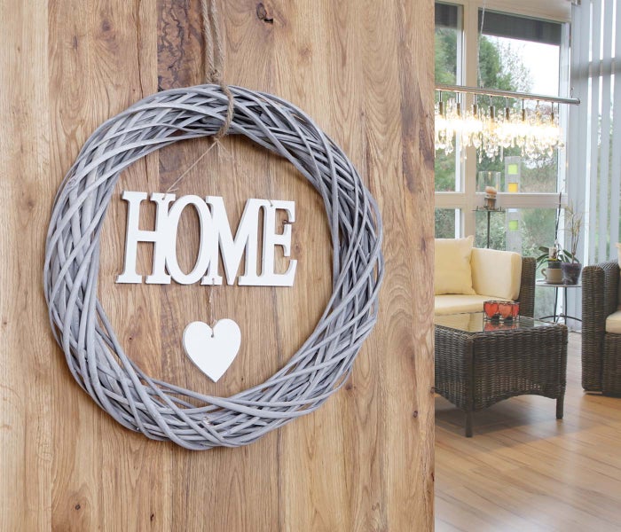 Dekorativer Kranz mit dem Wort HOME und einem Herz an einer Holzwand