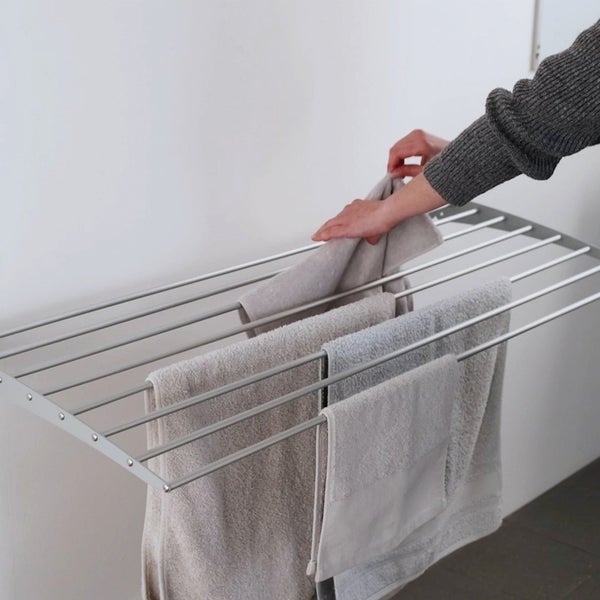 Wäscheständer mit aufgehängten Handtüchern und einer Person, die ein Handtuch aufhängt