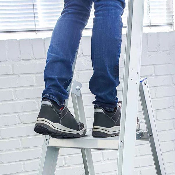 Person steigt auf eine Aluminiumleiter