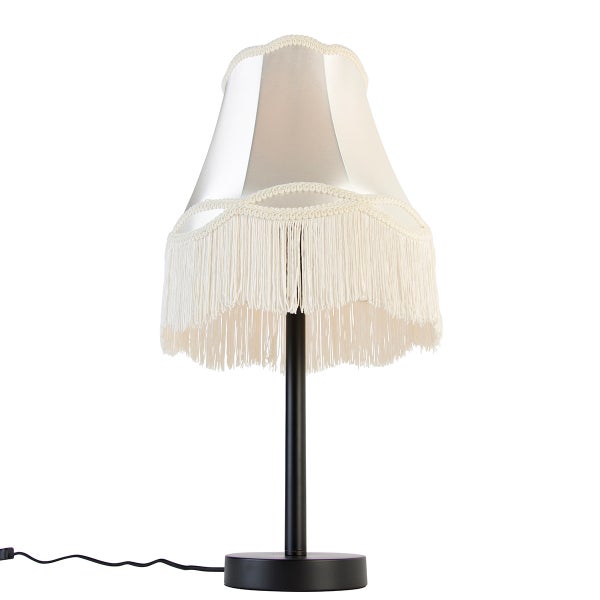 Tischleuchte mit schwarzem Metallfuß und hellem Textilschirm mit Fransen.