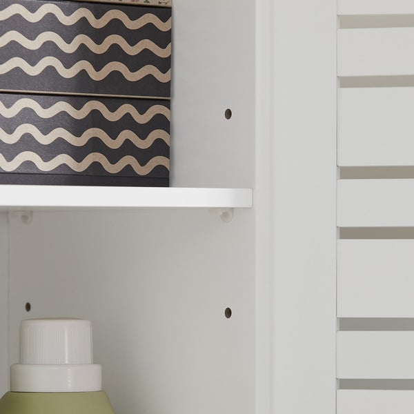 Detailansicht eines weißen Badezimmerschranks mit Einlegeböden und einer Box mit Wellenmuster