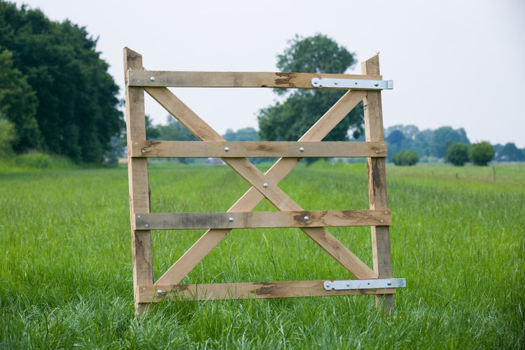 Holztor für Garten oder Weide aus Holzlatten mit Metallbeschlägen auf einer grünen Wiese.