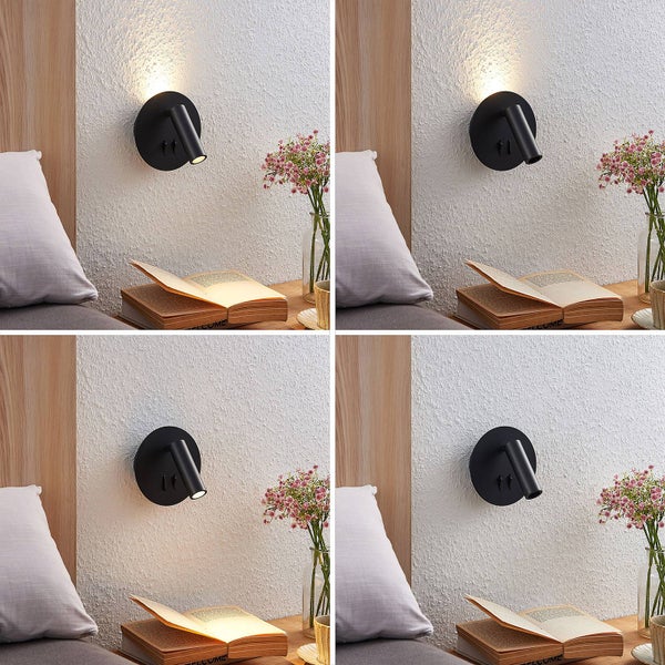 Schwarze Wandleuchte mit verstellbarem Leselicht und indirektem Backlight an einer strukturierten Wand über einem Nachttisch mit Buch.