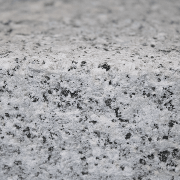 Nahaufnahme einer Granit-Natursteinoberfläche mit gesprenkelter Textur und sichtbarer Kante.