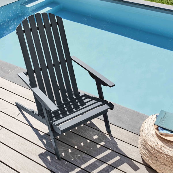 Grauer Adirondack-Gartenstuhl aus Holz auf einer Holzterrasse neben einem Swimmingpool.