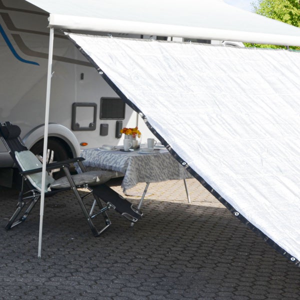 Organisierter Außenbereich mit Sonnenschutz an einer Wohnmobilmarkise sowie Campingtisch und Klappstuhl aus Metall und Stoff.