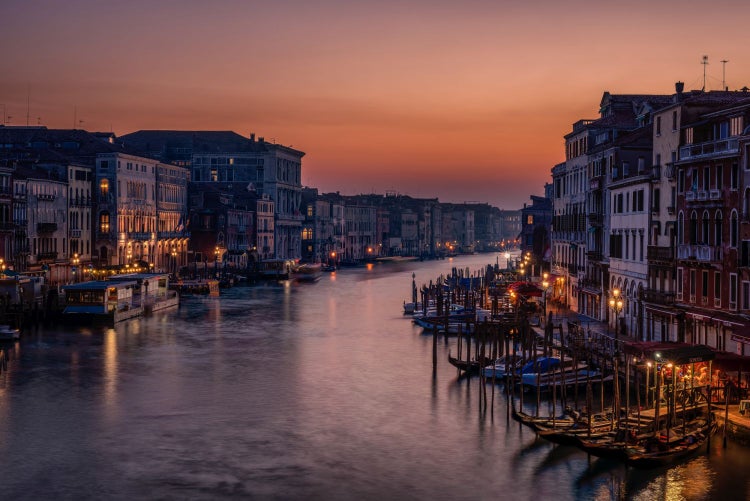 Ansicht des Canal Grande in Venedig bei Dämmerung mit beleuchteten Gebäuden und Gondeln