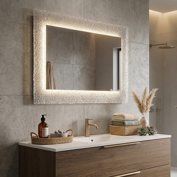 Moderner Badezimmerspiegel mit LED-Rahmen aus Strukturglas über einem Holz-Waschtisch mit goldener Armatur und grauen Wandfliesen in Betonoptik.