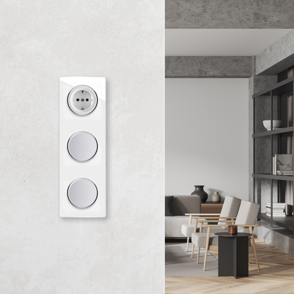 Eine dreifache Kombination aus Schuko Steckdose und zwei Lichtschaltern auf einer Wand vor einem modern eingerichteten Wohnzimmer.