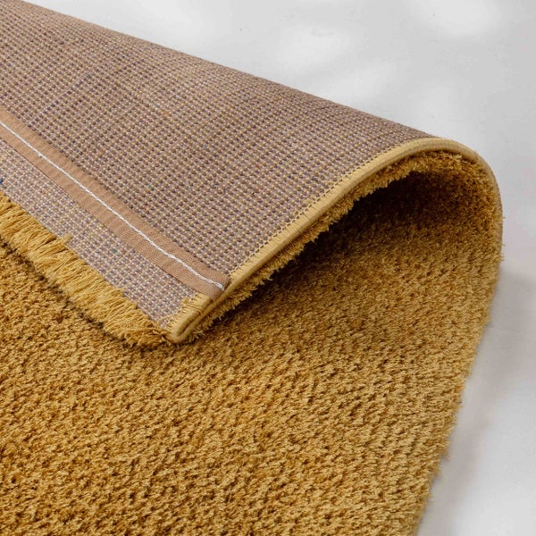 Gelber Hochflor-Teppich mit gewebter Rückseite und Fransen an der Kante.