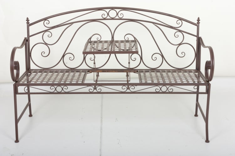 Braune Gartenbank aus Metall mit verzierter Rückenlehne und integriertem, hochklappbarem Mitteltisch.