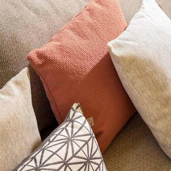 Verschiedene Zierkissen mit Textilbezug auf einem Sofa.