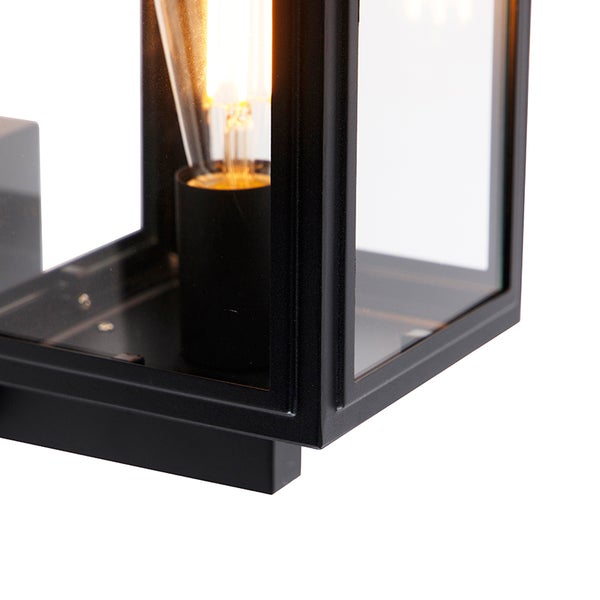 Detail einer modernen Wandleuchte mit schwarzem Metallrahmen, Glasscheiben und leuchtendem Filament-Leuchtmittel.