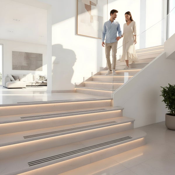 Helles, modernes Wohninterieur mit einer Treppe, die durch integrierte Stufenbeleuchtung und ein Glasgeländer in Szene gesetzt wird.