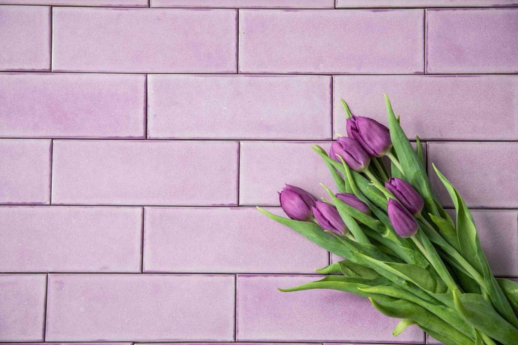 Rechteckige Wandfliesen im Mauerverband mit einem Strauß Tulpen.