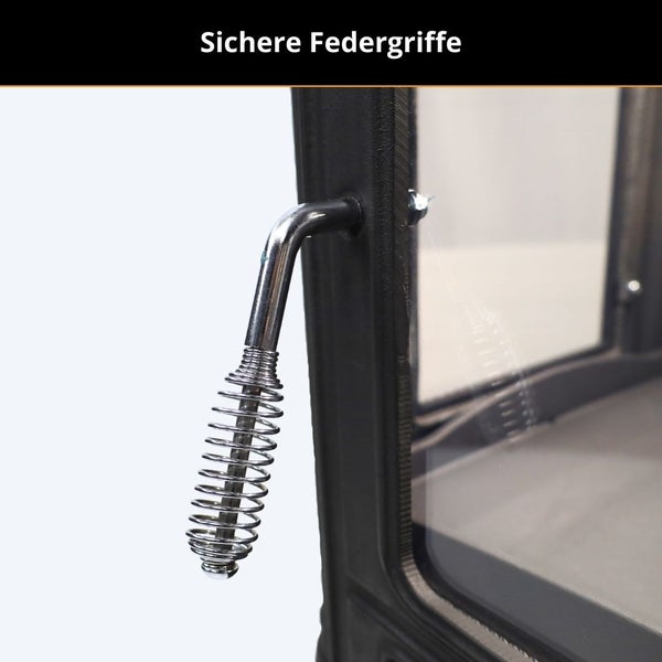 Sicherer Federgriff aus Metall an einer schwarzen Kamintür.