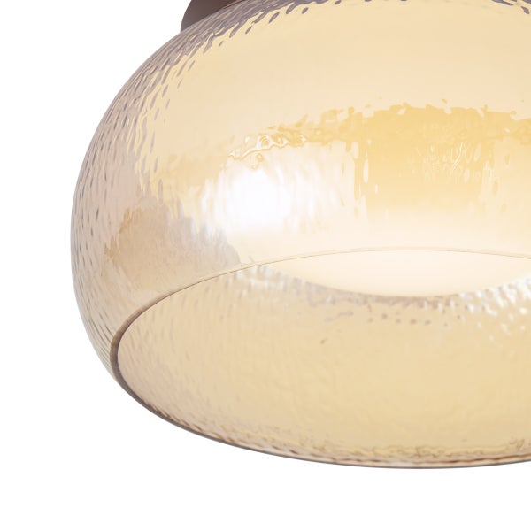 Detailaufnahme eines Lampenschirms aus strukturiertem Glas mit bernsteinfarbener, glänzender Oberfläche.