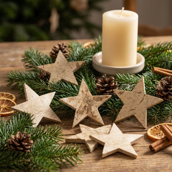Weihnachtliche Tischdekoration mit Holzsternen Tannenzweigen Kiefernzapfen Zimtstangen Orangenscheiben und einer Stumpenkerze auf einem Holztisch