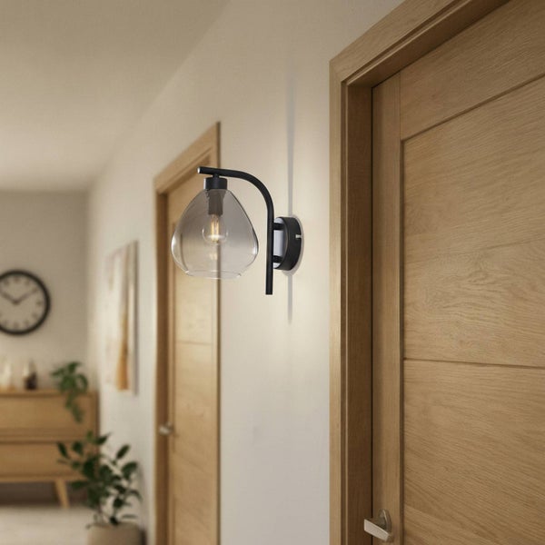 Wandleuchte mit Glasschirm und schwarzer Halterung in einem Flur