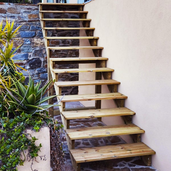 Holztreppe im Außenbereich mit Steinmauer und Bepflanzung